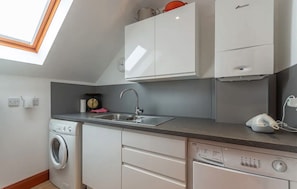 A compact kitchen with a washing machine, a sink, and a dishwasher. - Pipeland Farm Steading (No 4) (St Andrews)