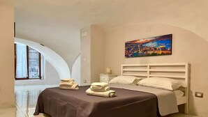 A bedroom with a bed, a nightstand, a painting, and a window with curtains. - House Of Fabio | A traditional townhouse in the historic center, surrounded by art and history (Napoli)