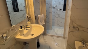 Een moderne badkamer met een grote spiegel, een wastafel, een douche en een bad.