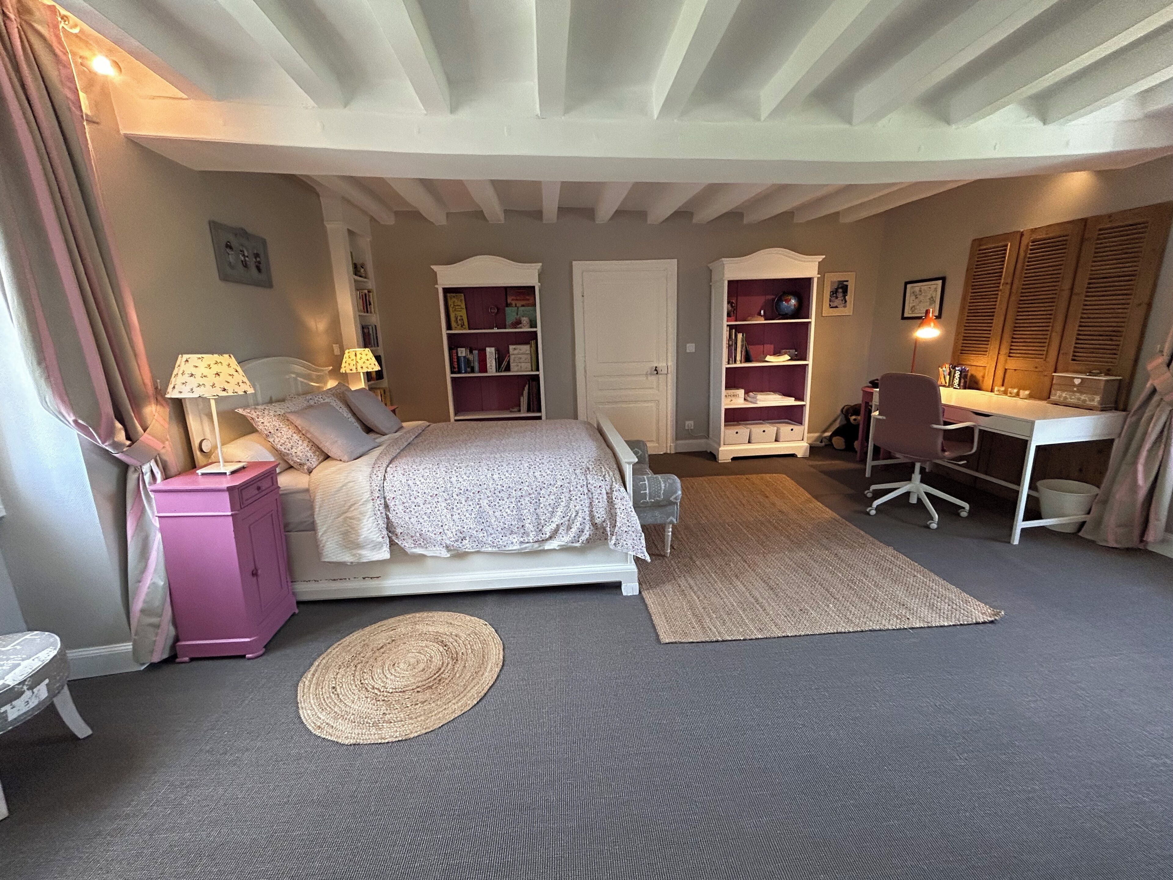 A bedroom with a bed, bedside tables, a desk, a chair, and a bookshelf.