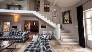 Ein geräumiger Wohnbereich mit hoher Decke, einer Treppe zu einer oberen Ebene und einem Essbereich im Hintergrund.