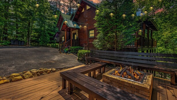Une cabane en bois dotée d’une terrasse, d’un foyer et d’un espace extérieur aménagé et abrité.