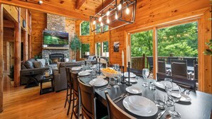 L’intérieur d’un chalet en bois comprend une cheminée, un coin repas aménagé pour six personnes et un salon confortable avec un téléviseur.