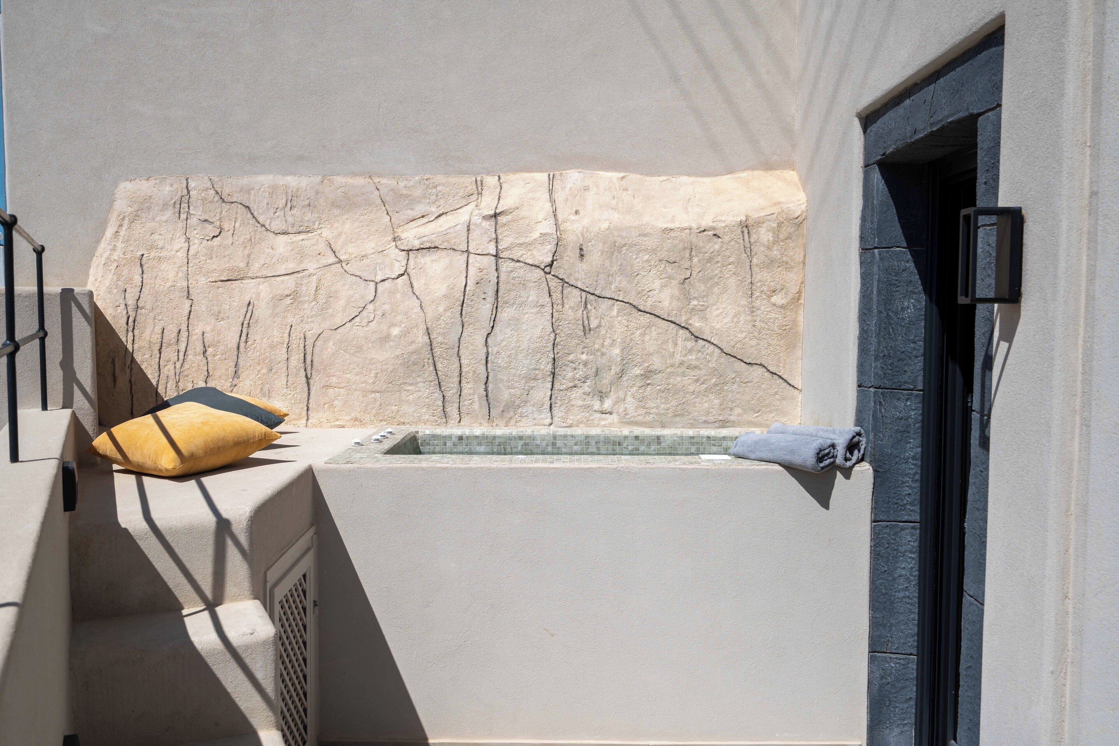 A spa area with a stone wall, a bathtub, and a towel.