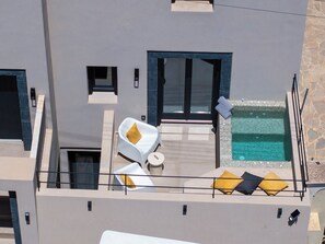 Une terrasse moderne sur le toit, dotée d’une piscine, de chaises longues blanches et d’un mur en pierre.
