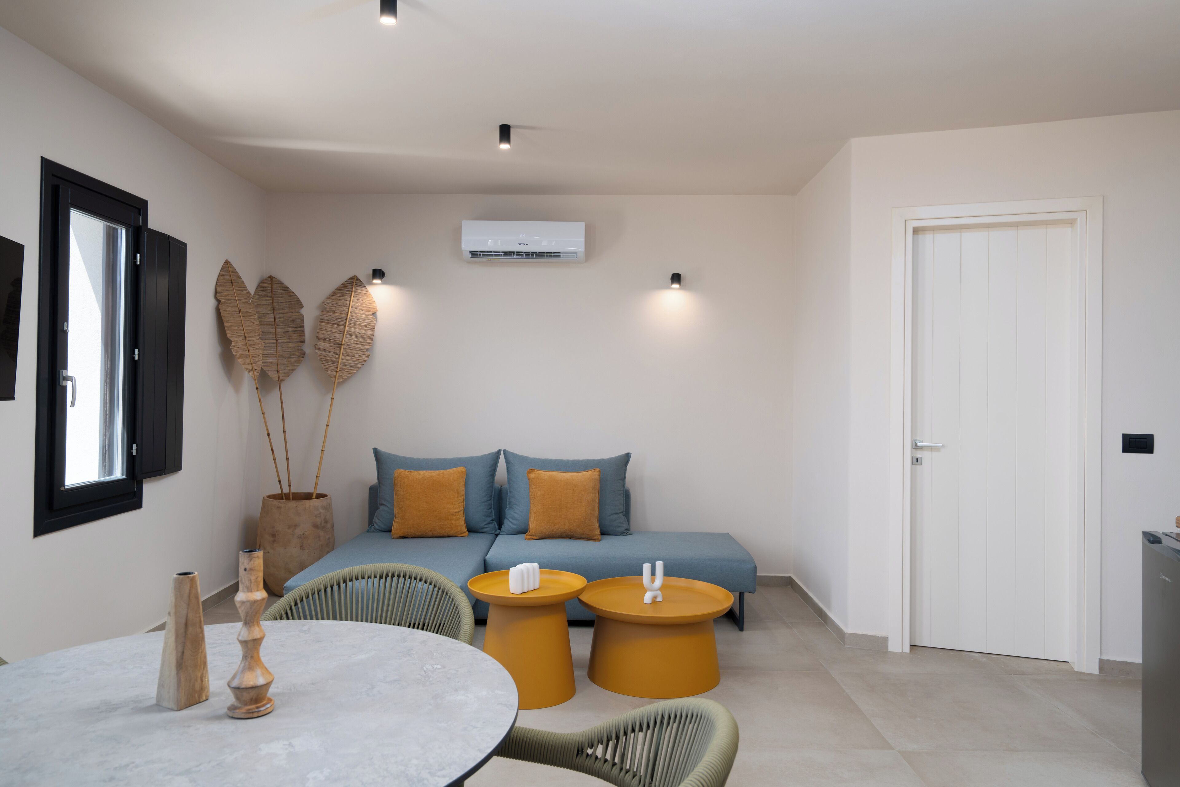 A modern living room with a sofa, two side tables, a round table, and decorative items.