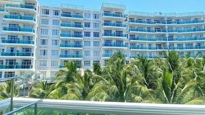 Un hotel de varios pisos con balcones y un área de piscina con palmeras.