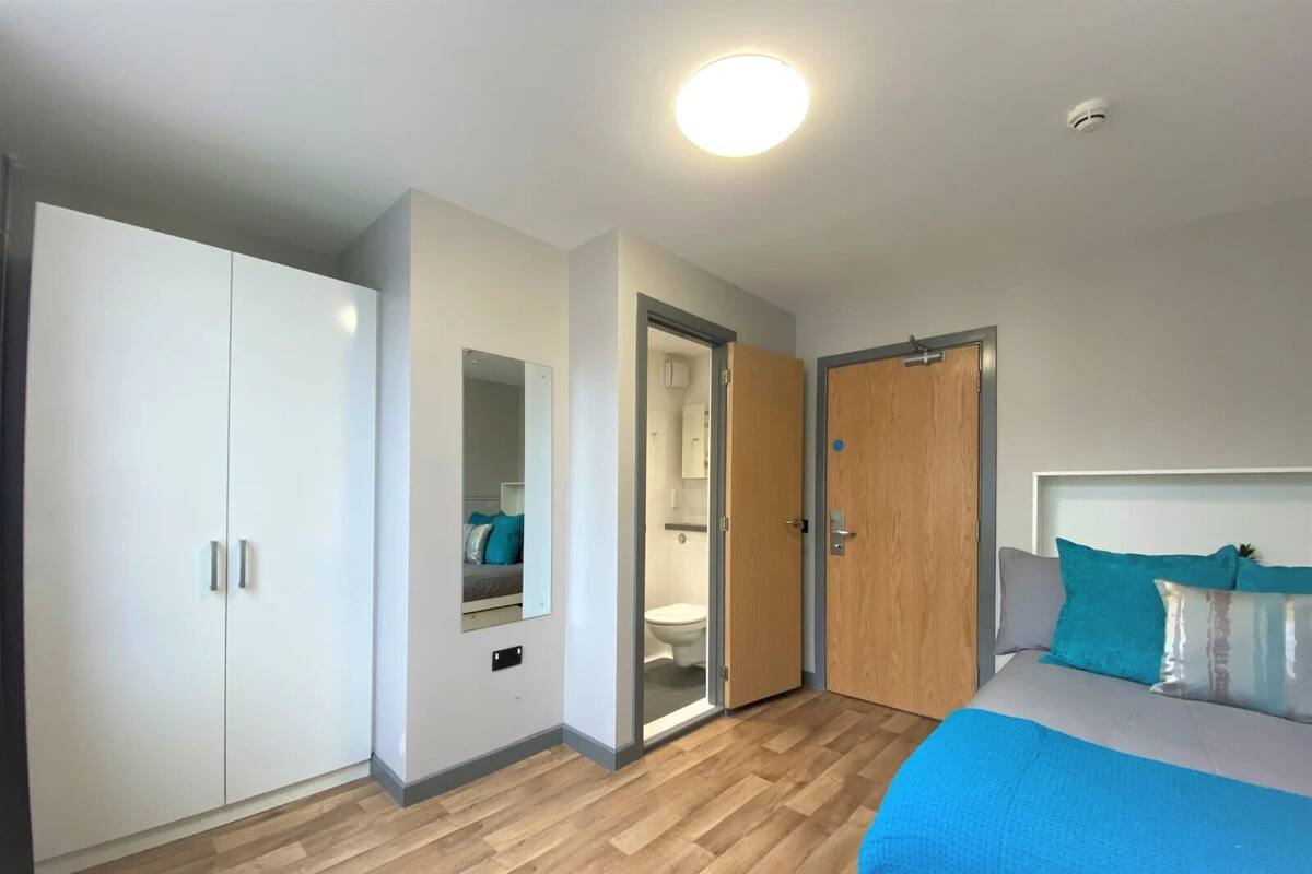 A bedroom with a bed, wardrobe, and a bathroom door.