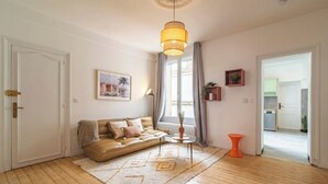 A living room with a sofa, a coffee table, a hanging light fixture, and a view of the outside. - Le Seventies - Exceptional 4 rooms & billiards (Reims)