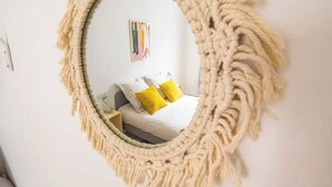 A round mirror with a macramé frame in a room with a bed, a nightstand, and a wall-mounted picture. - Le Seventies - Exceptional 4 rooms & billiards (Reims)
