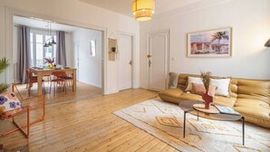 A living room with a sofa, a coffee table, and a dining area with chairs and a table. - Le Seventies - Exceptional 4 rooms & billiards (Reims)