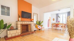 A living room with a fireplace, a television, and a dining area with chairs and a table. - Le Seventies - Exceptional 4 rooms & billiards (Reims)