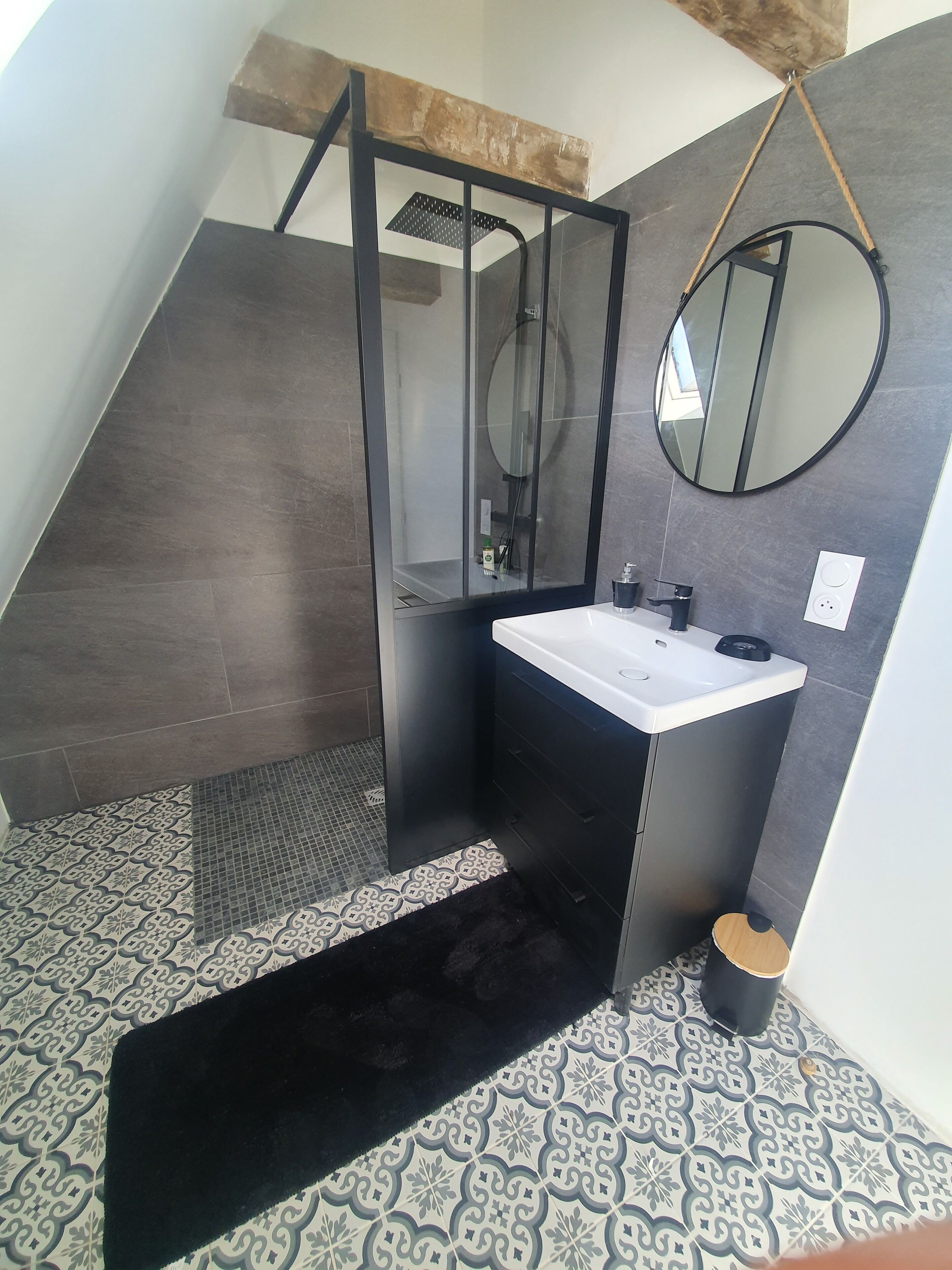 Une salle de bain moderne avec une douche à parois de verre, un lavabo blanc et un grand miroir.