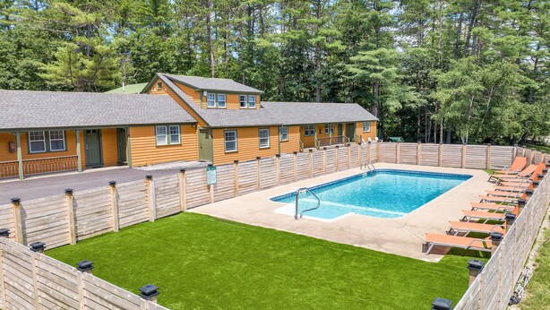 Un espace piscine doté d’une terrasse en bois, d’une piscine et de chaises longues.