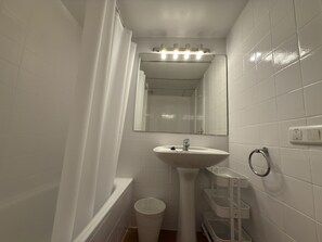 A bathroom with a white sink, mirror, and shower curtain. - HomeHolidaysRentals Roure - Costa Barcelona (Calella)