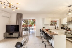 Eine moderne Küche mit Fernseher, Barhocker und einem Essbereich mit Tisch und Stühlen.
