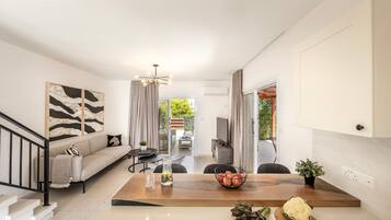 A modern living room with a sofa, coffee table, and a dining area.