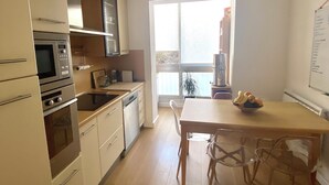 A modern kitchen with built-in appliances, a dining area with a table and chairs, and a large window providing natural light. - Charming duplex apartment in town center (Corte)