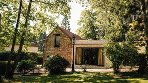 Un bâtiment en pierre avec un toit en pente, une grande fenêtre et une petite porte.