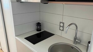 A compact kitchen with a built-in microwave, a stainless steel sink, and a black induction cooktop. - Comfort Studio in a Premium Residence- Sport/cinema (Huningue)