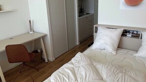 A hotel room with a bed, a desk, a chair, a kitchenette, and a wardrobe. - Comfort Studio in a Premium Residence- Sport/cinema (Huningue)