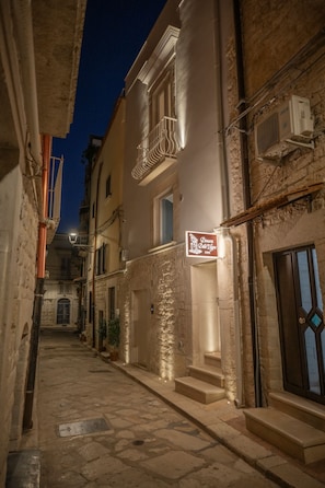 A narrow street with stone pavement, a building with a sign reading "Olimpia 101 Della Lira," and a staircase leading to an entrance. - Dimora Delle Vigne (Andria)