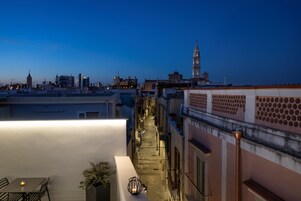 Terraza en la azotea con vistas al horizonte urbano, incluyendo una torre destacada.