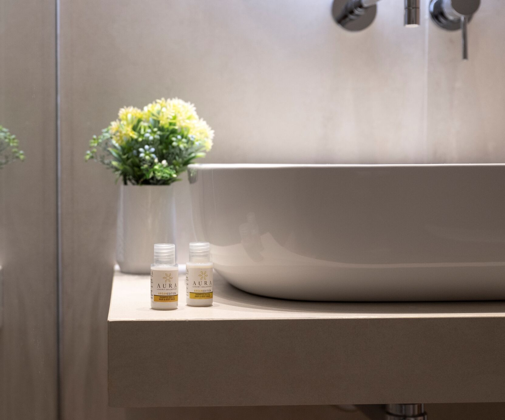 A bathroom with a large bathtub, a small potted plant, and two bottles of shampoo on the counter.