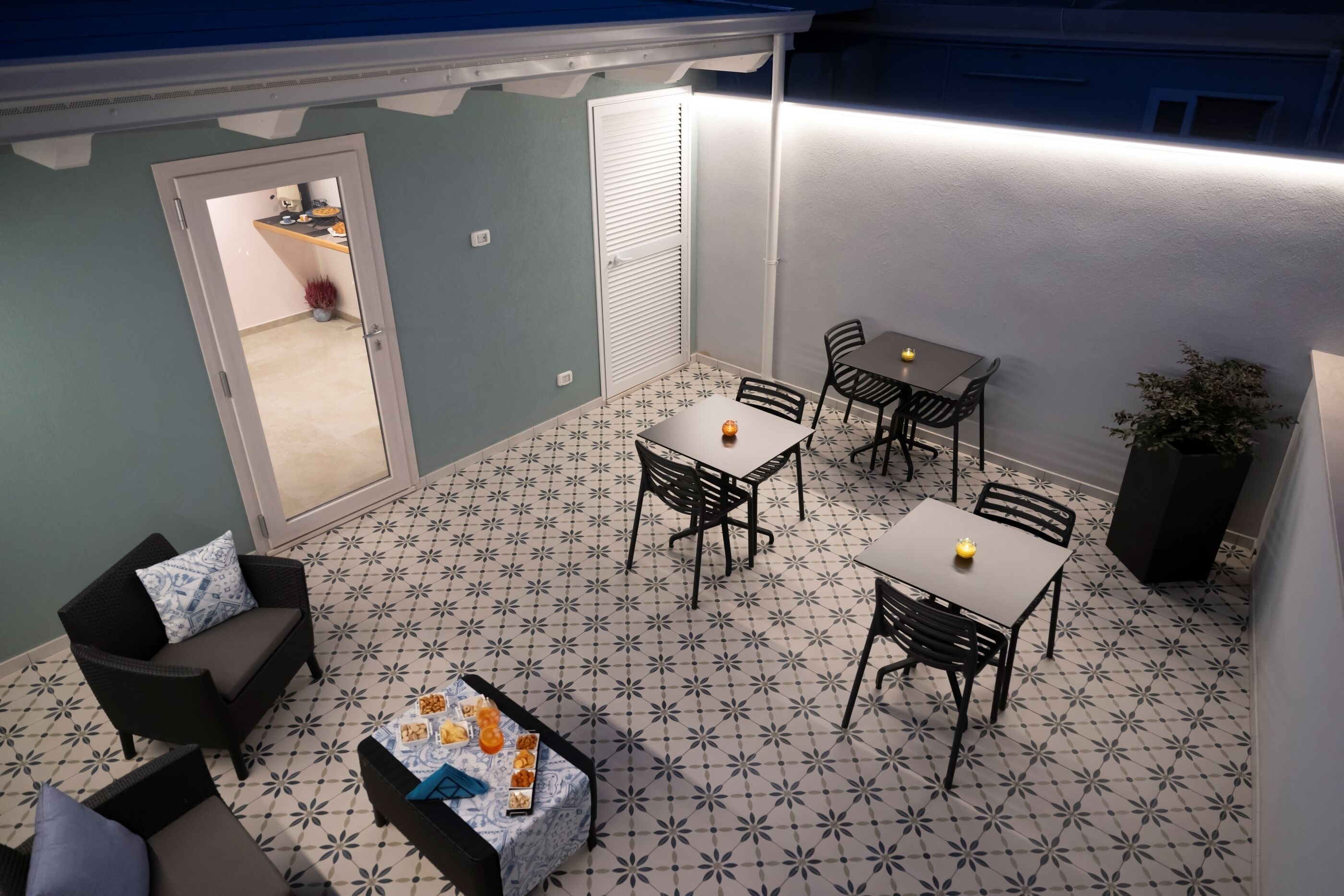 Un patio con una mesa y sillas de comedor, un sofá y una pequeña mesa con aperitivos.