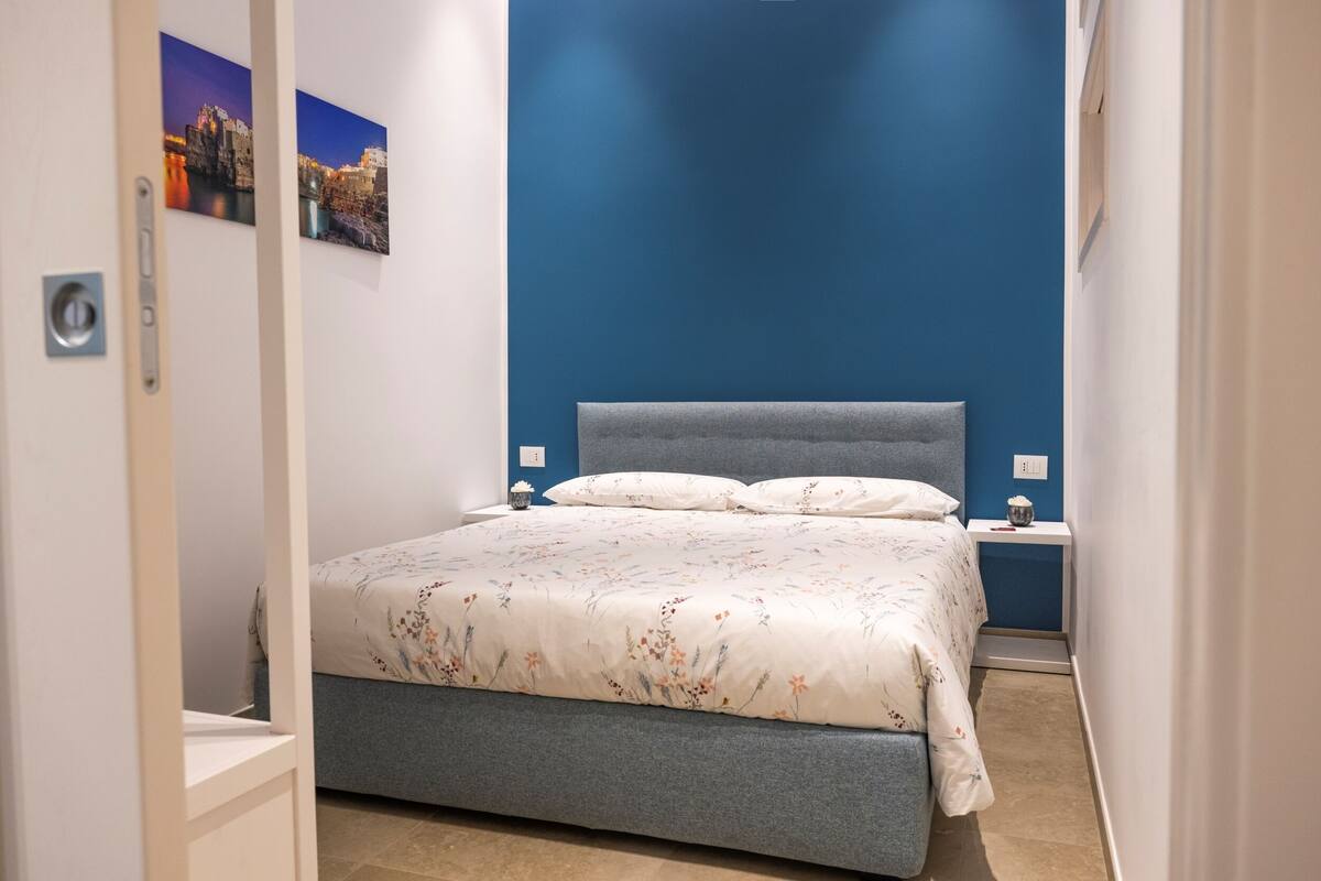 Un dormitorio con cama, mesitas de noche y cuadros en la pared.
