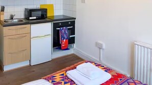 Cocina compacta con microondas, lavamanos y horno. Cuenta con una pequeña encimera y armarios de madera.