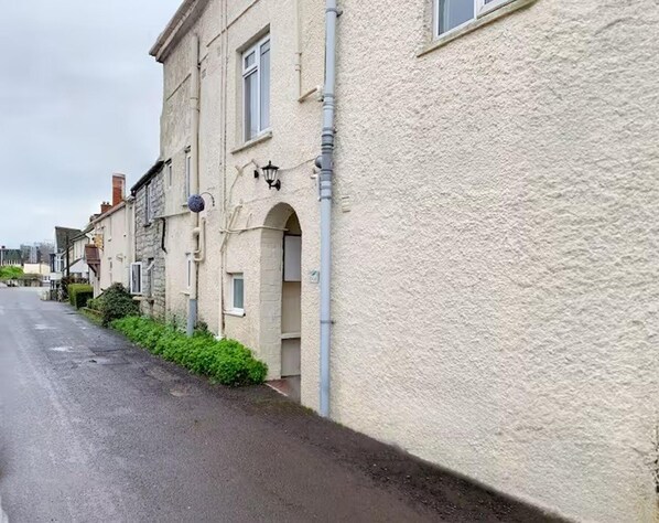 Una estrecha calle bordeada de edificios tradicionales de piedra, con ventanas de arco y un farol.