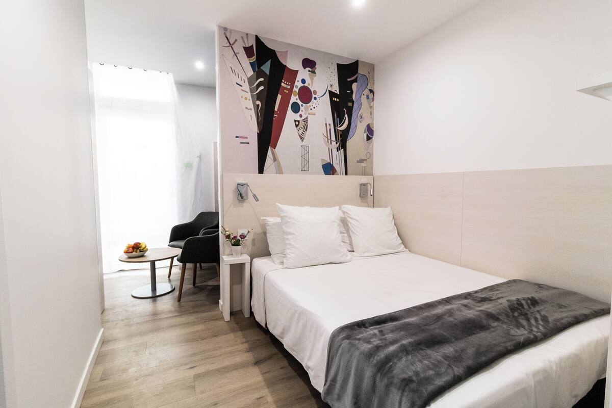 Ein modernes Hotelzimmer mit einem Bett, einem kleinen Schreibtisch und einem Sessel.