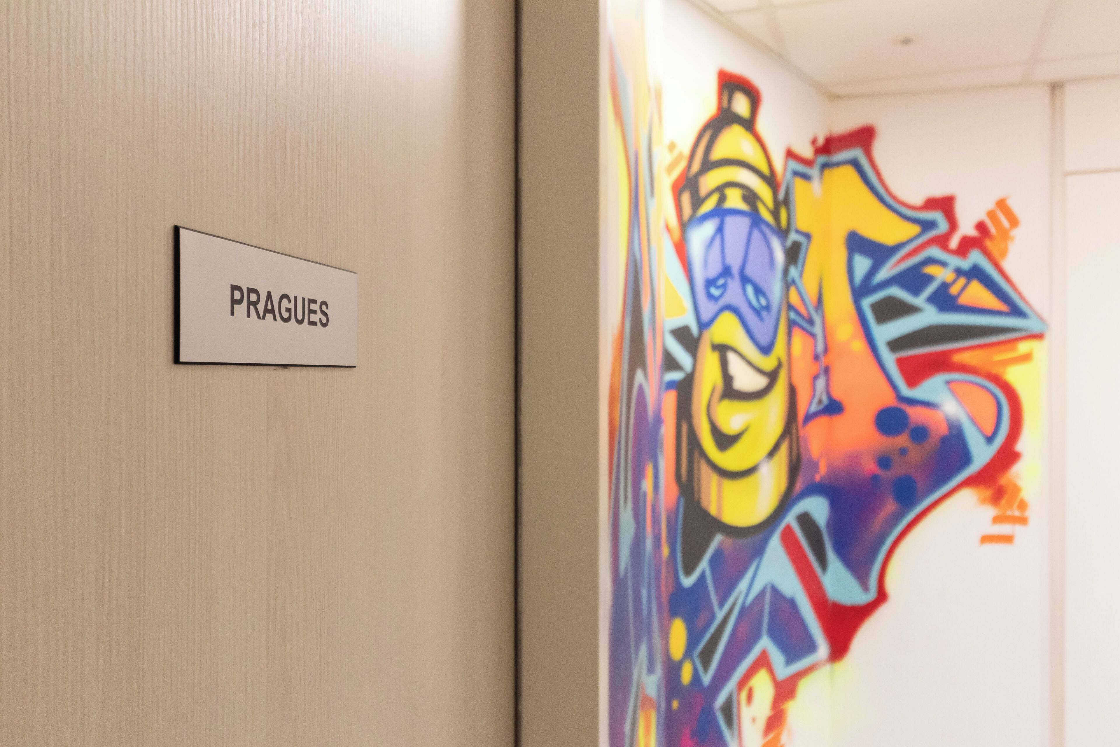 Un pasillo con un letrero que dice 'PRAGUES' y una pared cubierta de grafitis coloridos.