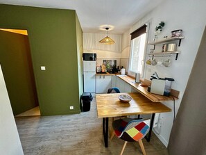 Eine kleine Küche mit Mikrowelle, Kühlschrank und Holztisch.