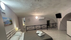 A bedroom with a bed, a nightstand, a wall-mounted TV, and a painting.