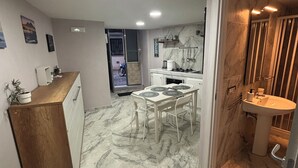 A compact kitchen with a dining area, a sink, and a small bathroom.