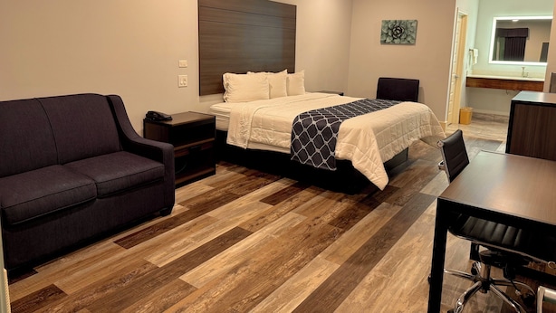 A hotel room with a bed, a sofa, a desk, and a chair. - Garden Inn Express (Humble)
