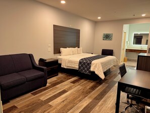 A hotel room with a bed, a sofa, a desk, and a chair.
