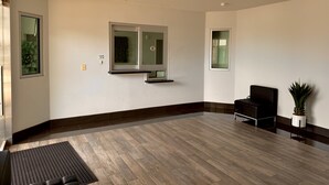 A spacious room with a large window, a black chair, and a potted plant. - Garden Inn Express (Humble)
