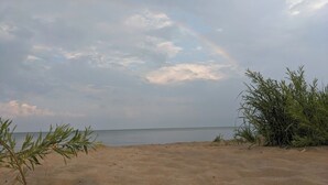 Une plage avec un ciel dégagé et un arc-en-ciel.
