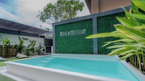 A swimming pool with a green wall and a motivational quote.