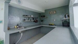 A kitchen with a sink, shelves, and a microwave.