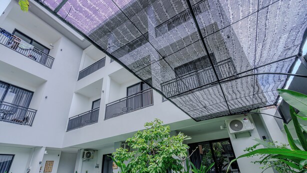 A multi-story building with balconies, air conditioning units, and potted plants.