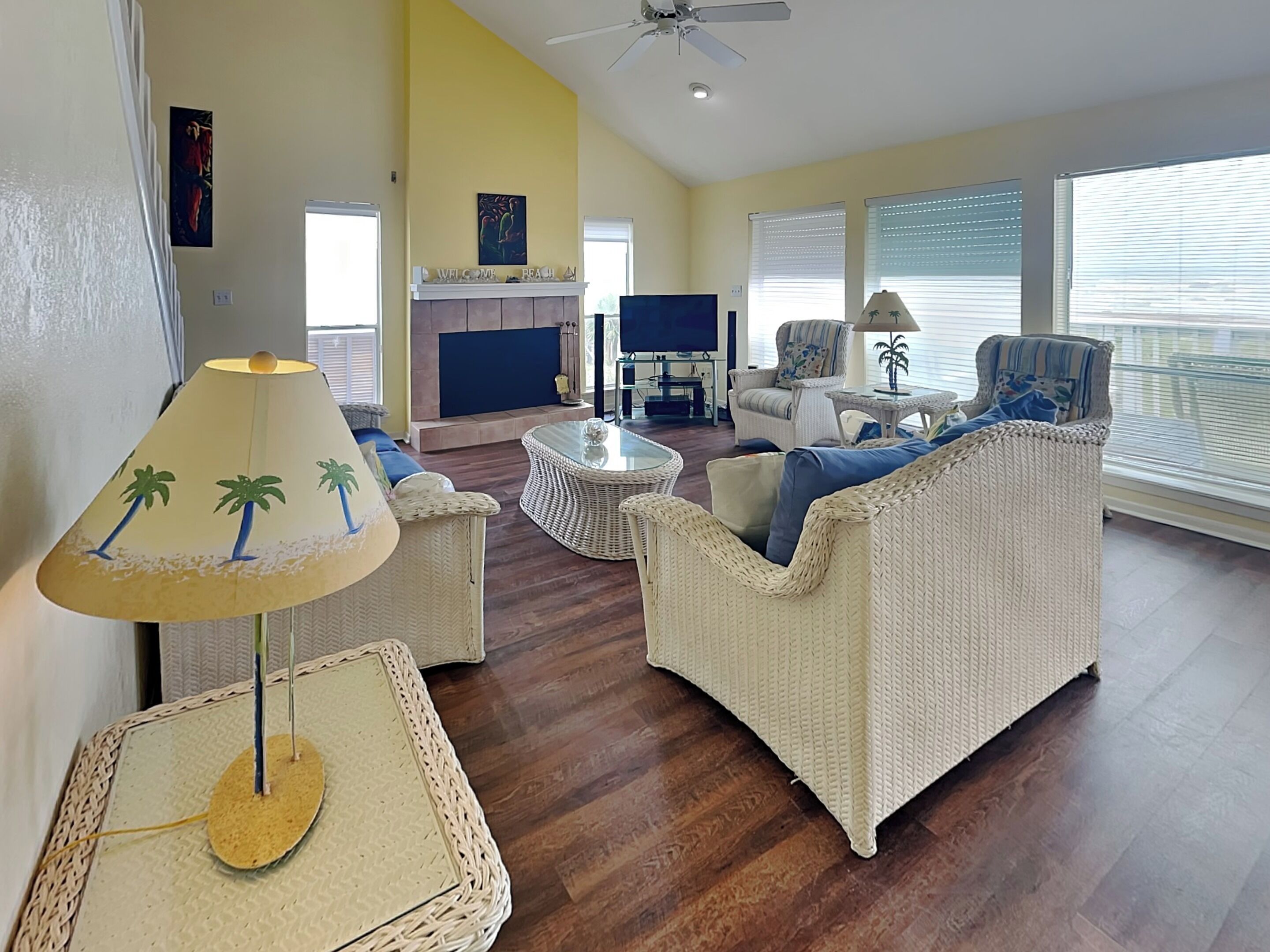 A living room with wicker furniture, a fireplace, and a television.