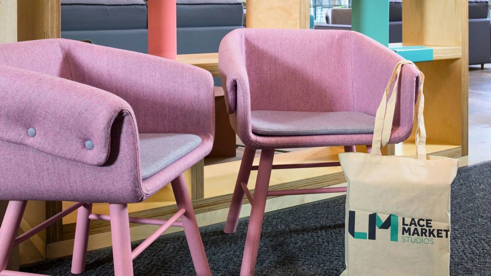Dos sillas rosas con un cojín de asiento gris en una habitación con alfombra gris.