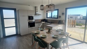 Moderni keittiö, jossa on ruokailutila, suuret ikkunat ja näkymä ulos.