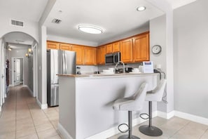 Uma cozinha moderna com armários de madeira, eletrodomésticos de aço inoxidável e uma ilha central com banquetas.