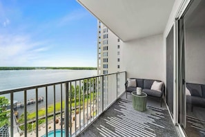 A balcony with a view of a body of water, a sofa, and a small table.