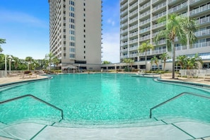 A swimming pool with a clear blue water, surrounded by a building with multiple floors and balconies.